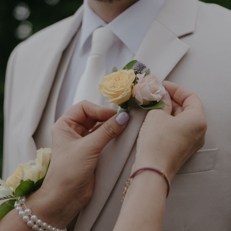 Boutonniere being pinned onto a groom's lapel